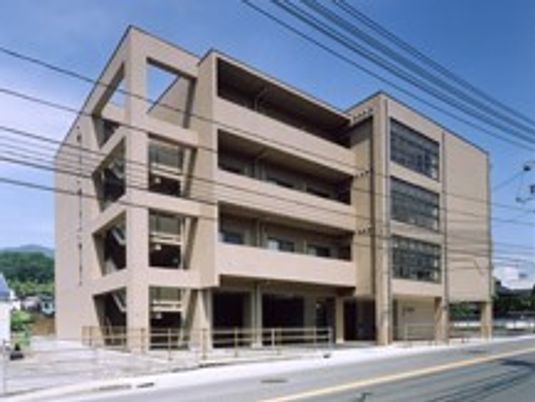 ブラウンを基調とした４階建ての建物。各フロアにベランダが付き、屋外避難用の階段もある。
