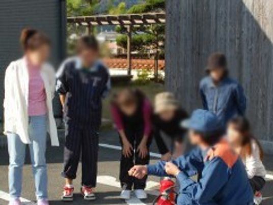 消防士に消火器の使い方についての説明を受けている女性スタッフたち。