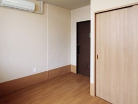 エアコン付きのフローリングの部屋にはクローゼットが付き、家具や家電が置かれている。