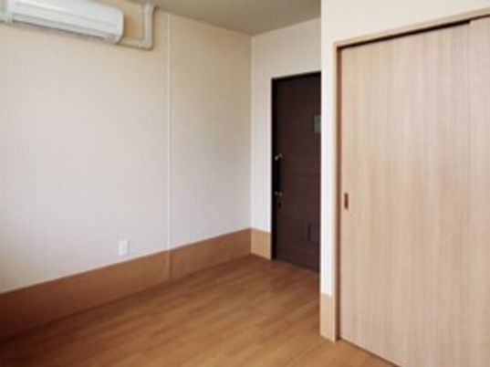 エアコン付きのフローリングの部屋にはクローゼットが付き、家具や家電が置かれている。