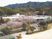 建物を含む遠景。学校の校庭のような広場から通りを挟む位置に桜や建物がある。