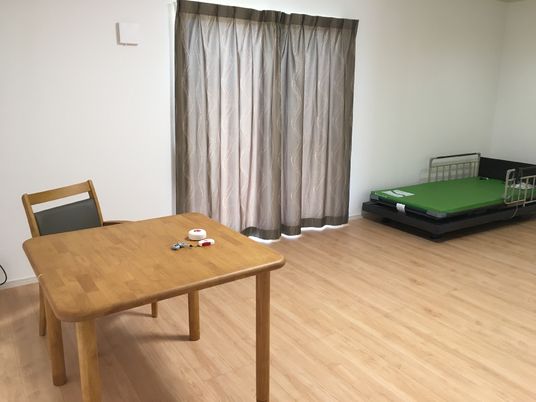 椅子と机、ベッドが並んでいる部屋。窓にはカーテンがかかっている