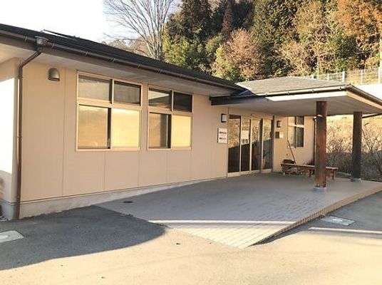 平屋建ての建物の玄関には大きな車寄せが付き、ベンチがあり、自然に囲まれている。