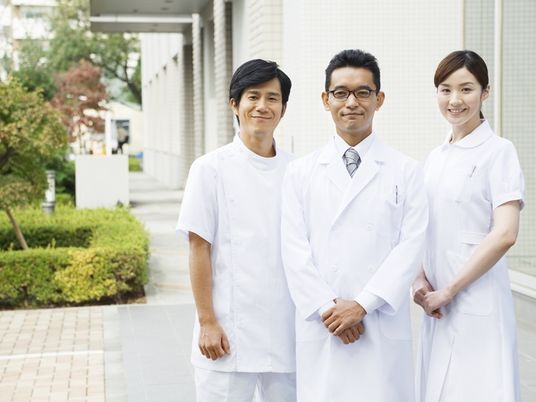 医師と看護師がこちらを向いてほほ笑んでいる写真。何かを眺めている様子