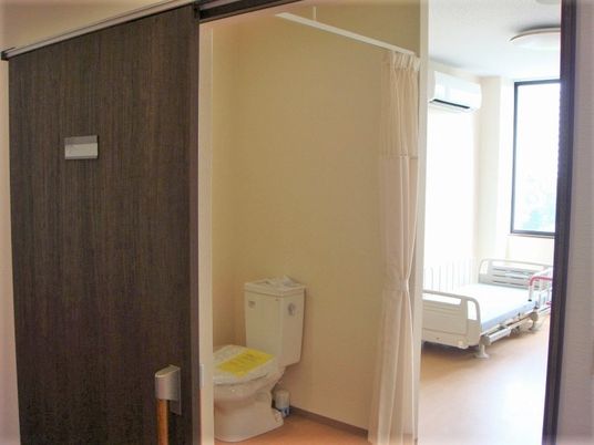 ドアレスのトイレが付いている個室の様子。奥のほうにベッドが置いてあるのが分かる