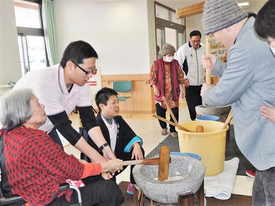 もちつきを楽しんでいる様子の高齢者とスタッフ。施設内のイベント時の写真