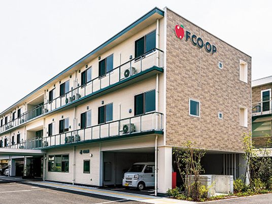 3階建ての建物は横に長く、レンガ調の外壁には住宅名が書かれ、シンボルマークのリンゴの絵もある。