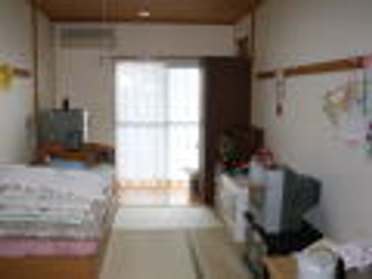 畳敷きの和室は大きな窓が付き、日当たり良好。明るい雰囲気の部屋にはタンスなどの家具なども置かれている。