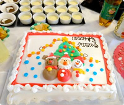 サンタクロースやトナカイ、スノーマンなどが飾られたケーキの枠は赤く、はなみずきクリスマスと書かれている。