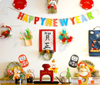 賀正と書かれた紙やHAPPYNEWYEARのガーランド、お屠蘇セットや鏡餅などが飾られている。