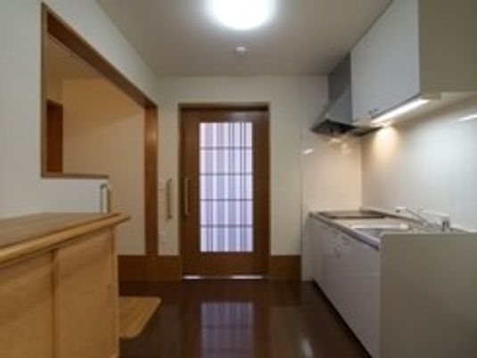 施設内に用意されているキッチンスペースとドア、木製の家具類が写っている