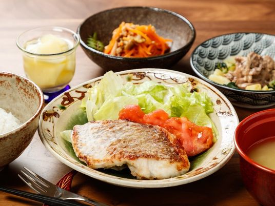 魚のグリルにはサラダが添えられ、ニンジンのきんぴら、野菜の煮物、みそ汁や白いご飯が並んでいる。