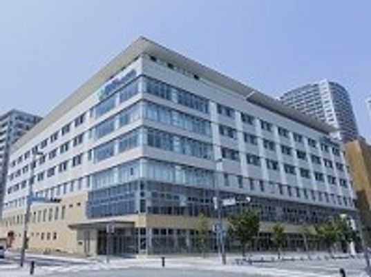 道路に面して建っている大きな病院の周りにはたくさんのビルがあり、日当たりのいい場所。