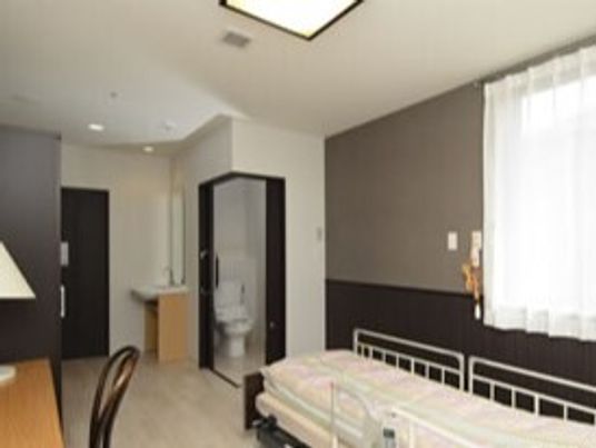 寝具付きのベッドやデスクセット、クローゼットが付いたフローリングの部屋。トイレもある。