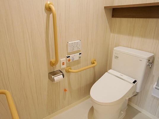 Ｌ字型の手すりがある高齢者向け施設のトイレ。緊急コールが取り付けられている