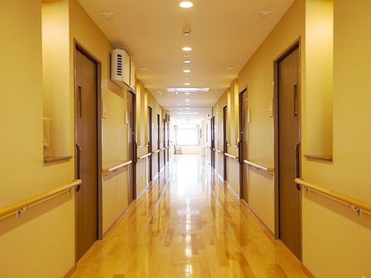 施設内にあるまっすぐに続く廊下の様子。両側に手すりがあり個室のドアがある