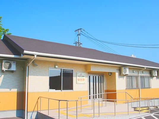 グレーの屋根が付いた平屋建ての建物の玄関には手すり付きのスロープがある。