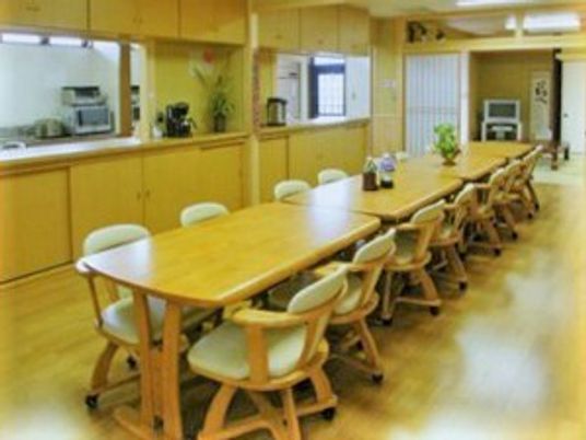 木製のダイニングテーブルがつなげて並べられ、奥には和室、横にはキッチンもある。