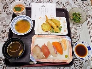 赤だしと握りずし、てんぷらが乗っている豪華な行事食の写真
