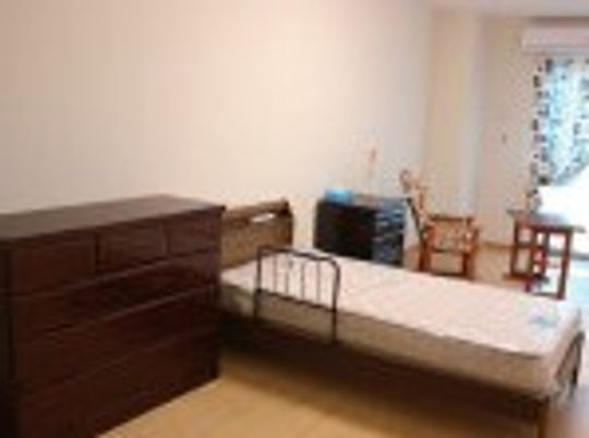 介護ベッドが置かれた部屋には大きなタンスやエアコンな度も設置され、窓にはカーテンがある。