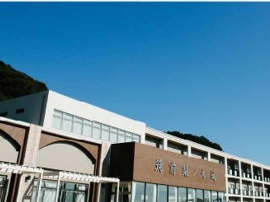 青い空の下に建っている横に長い建物にはベランダが付き、大きな文字でホーム名が書かれている。