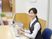 椅子に座った女性スタッフが微笑みかけながら業務を行っている。
