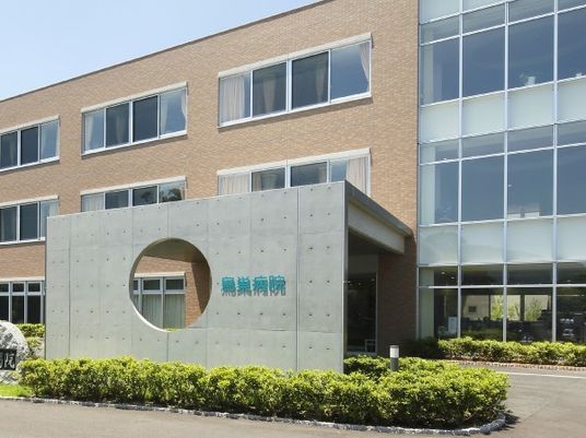 茶色い壁とガラス貼りの建物。入り口の穴あきの看板が特徴的である