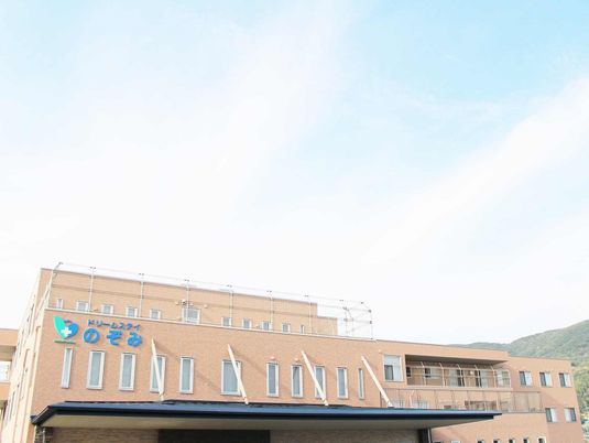 介護付き施設「ドリームステイのぞみ」の外観。やわらかい色合いの建物の写真