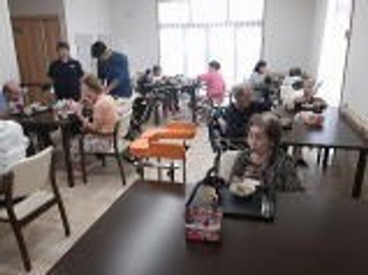 共有スペースで思い思いの場所に座り、食事を楽しむ入居者と見守るスタッフ。
