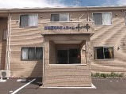 ２階建ての建物を正面から見た様子。玄関周辺にはプランターが置かれている。