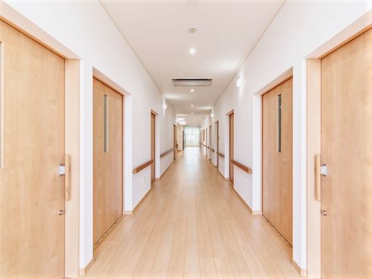 まっすぐな廊下には木製の手すりが付き、居室のドアはすべて引き戸となっている。
