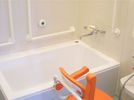 一人用の浴槽が置かれた浴室。手すりやシャワー、シャワーチェアも設置されている。