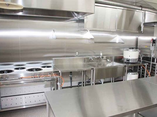 ステンレス製の本格的な厨房には収納もしっかりあり、大きな炊飯器もある。