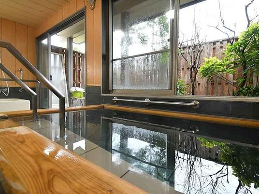 木製の枠が設置された大きな浴槽には手すりや階段が付き、外の景色を眺めることができる。