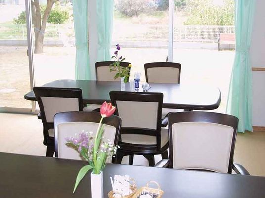 ４人掛けのダイニングテーブルの上には季節の花が飾られ、窓の外には庭が見える。