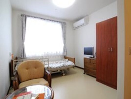 タンスやテーブル、椅子、介護用ベッドなどが置かれている施設内の居室