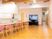広めのフローリング仕様の部屋に椅子と机が並んでいる。奥のほうにテレビがある様子