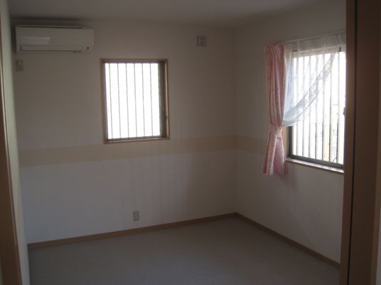 エアコンが付いたコンパクト名部屋には窓が二つあり、その内の一つにはカーテンが付いている。