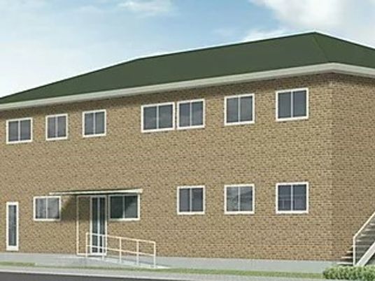 2階建ての建物はブラウン系で屋外階段や玄関先のスロープも付いている。