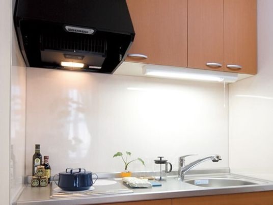 IHクッキングヒーター付きのキッチンは作業台が広く、収納も豊富についている。鍋や調味料が置かれ、レンジフードの照明も付いている。