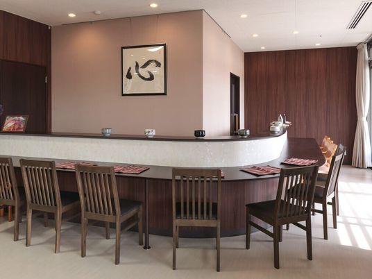 デザインの異なる湯飲みが飾られているカウンター席には椅子がセットされ、ランチョンマットが置かれている。