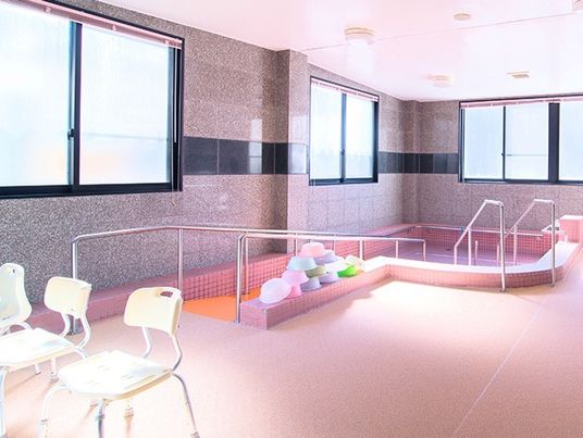 シャワーチェアが並ぶ大浴場の様子。手すりが付いたプールのような形の浴槽がある