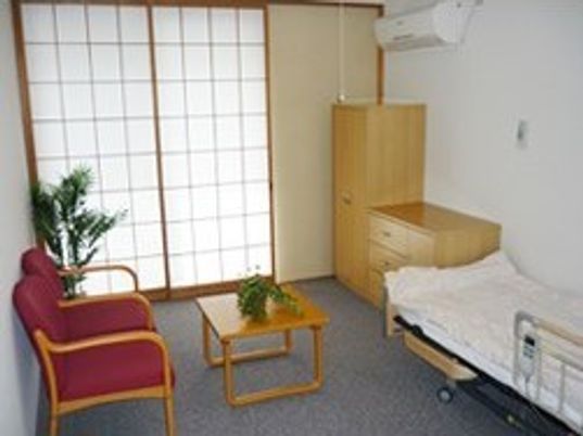 ベッドや収納、いす、テーブルがある部屋の様子。エアコン付きの和風の部屋