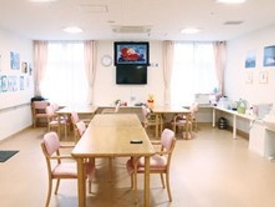 ダイニングテーブルが複数置かれた食堂は明るく開放的なスペース。壁には介護やテレビが飾られている。