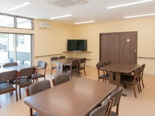 木製のダイニングテーブルが複数置かれている食堂には大きなテレビが付いている。