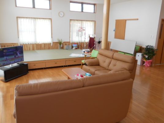 エル字型に設置された大きなソファがテレビを囲むようにしてあり、奥には畳の小上がりスペース。