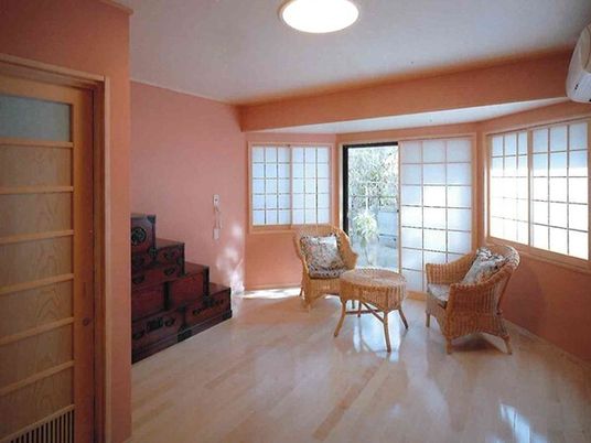 ラタン家具が置かれたフローリングの部屋には障子が設置された窓があり、レトロな引き出し家具も積み重ねられている。
