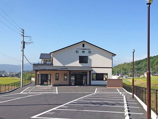 2階建ての建物。駐車スペースが広く、自然に囲まれた環境。
