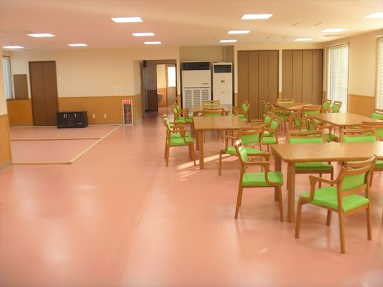 四人掛けのテーブルと椅子が並べられている施設内の共有スペースの様子