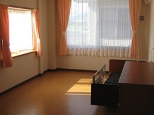 大きな窓が二つ付いたフローリングの居室には介護ベッドが置かれ、日当たりも良好。